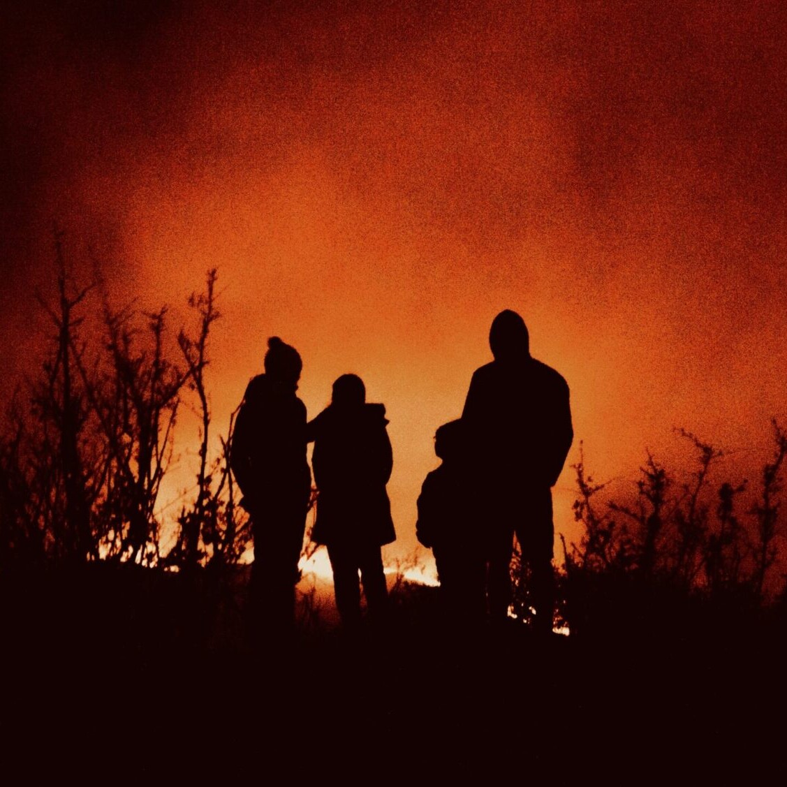 Family silhouetted by forest fire