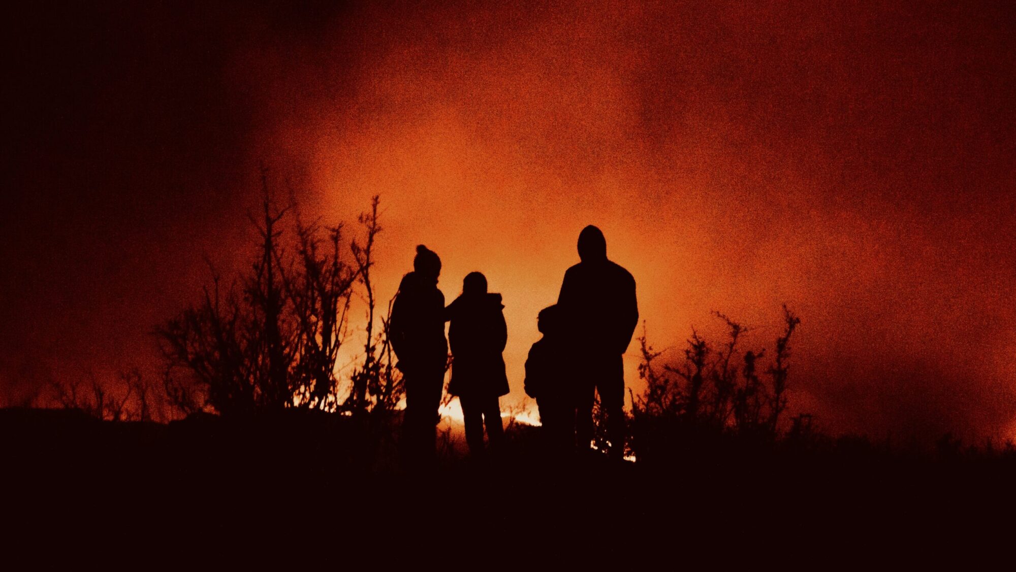 Family silhouetted by forest fire